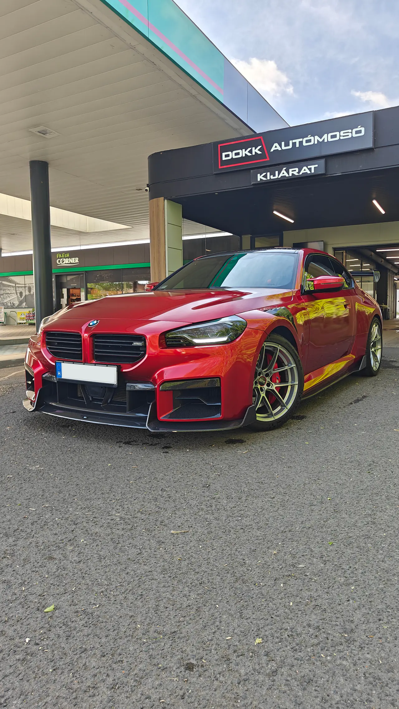 Piros BMW M2 kupé arany felnikkel a DOKK Autómosó 2 kijárata alatt